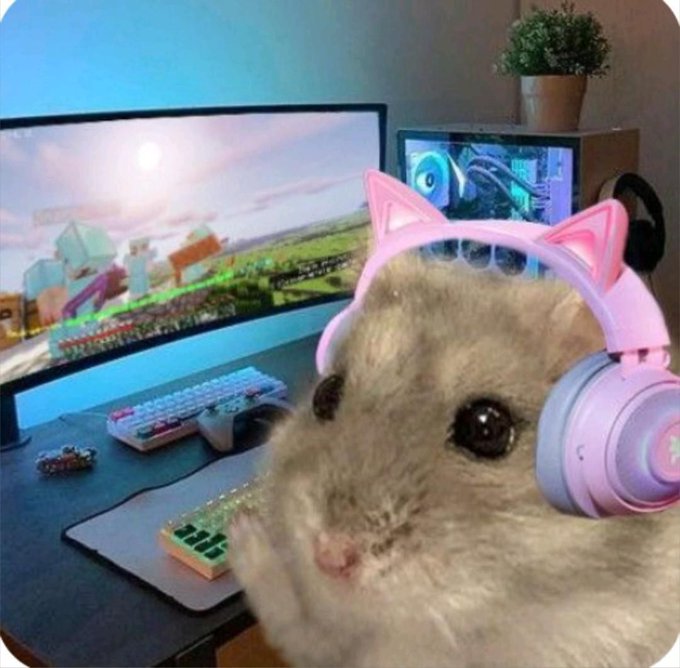 A humorous image of a hamster wearing pink cat-ear headphones in front of a computer setup featuring a Minecraft-themed monitor, a white keyboard, and a small keypad.