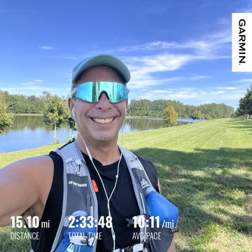 A man wearing a hydration vest and sunglasses takes a selfie after a run, with stats displayed: 15.10 mi distance, 2:33:48 total time, and 10:11/mi average pace, branded with 'GARMIN'.
