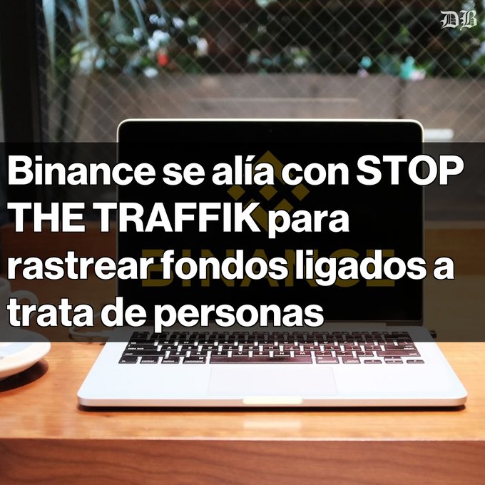 A laptop displaying the Binance logo sits on a wooden table, with a headline overlay reading "Binance se alía con STOP THE TRAFFIK para rastrear fondos ligados a trata de personas," referencing the cryptocurrency exchange's partnership with the anti-trafficking organization to track funds linked to human trafficking.