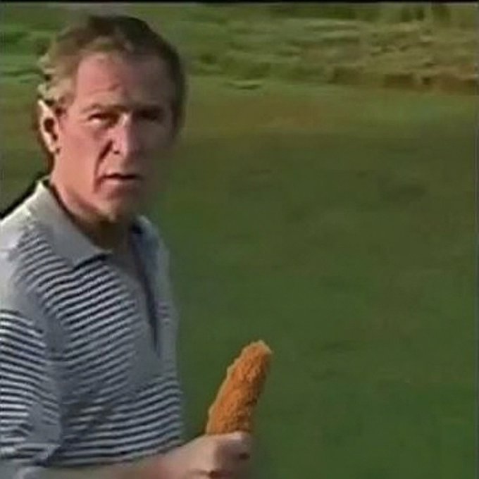 A man in a striped polo shirt holds a corn dog with a puzzled expression on a golf course, looking like he's been interrupted mid-swing—perfectly capturing the "babe wake up memecoins are so back" energy of someone dropping unexpected news that makes you do a double-take.