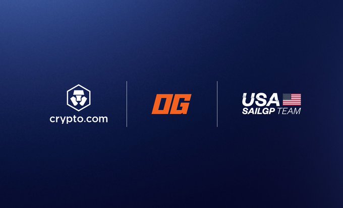 The image features a blue background with three logos, each representing a different company or organization. The first logo is for Crypto.com, the second logo is for OGC (Og), and the third logo is for SailGPUSA (SailGP). These logos are arranged in a horizontal line on the image, creating a sense of balance and symmetry. The text "Crypto.com/us/company-new" is located at the bottom right corner of the image, indicating that this collaboration is new and exciting to both companies involved.