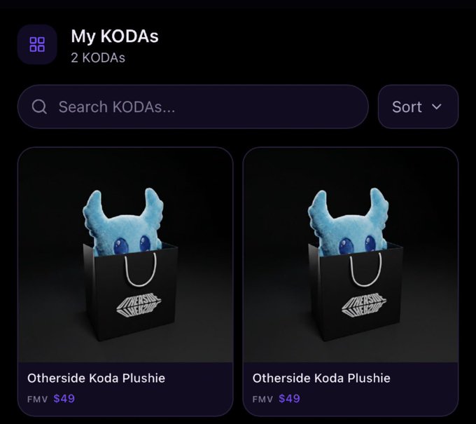 The image shows two blue plush toys sitting inside black bags, placed against a dark background. The text "My KODAS" is displayed at the top of the image, indicating that this is related to a discussion about kodas or a collection of kodas.