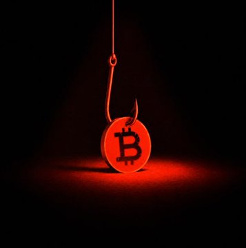 A Bitcoin logo appears as a fishing hook bait, illuminated by a red spotlight against a black background, symbolizing a phishing scam.