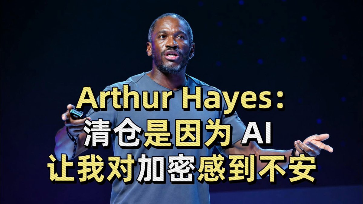 The image features a man standing against a dark background, holding a cell phone up to his face as if he's giving a speech or presentation. The text "Arthur Hayes" can be seen at the top of the image, indicating that this is an interview with Arthur Hayes. The man appears to be wearing a gray shirt and has a serious expression on his face.