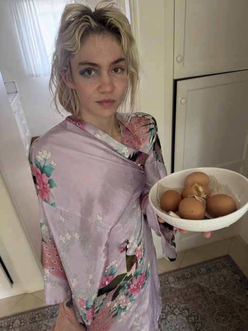 A young woman wearing a floral kimono and holding a white bowl filled with brown eggs in a kitchen.