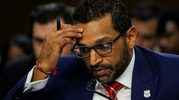 Kash Patel, wearing glasses and a dark blue suit with a red tie, appears to be testifying before Congress while holding a pen near his forehead.

The image relates to the post about FBI Director Kash Patel's late disclosure of his Bitcoin-stock purchase.