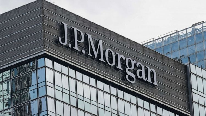 The image shows the exterior of a JPMorgan office building, prominently displaying the company's logo on the upper facade against a modern glass-paneled structure. The image visually reinforces the article about JPMorgan's stance on yield-bearing stablecoins, illustrating the financial institution issuing the warning about crypto products that could compete with traditional banking services.