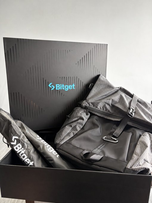 A black Bitget branded box contains a backpack and other promotional merchandise with the Bitget logo.