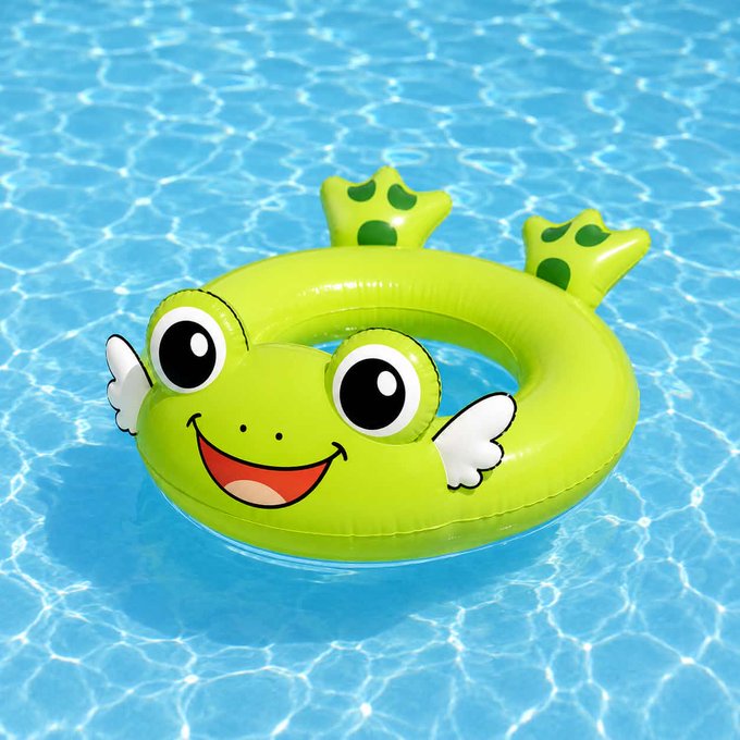 An inflatable green frog-shaped baby swim ring with a smiling face and small white wings floating in a blue swimming pool.