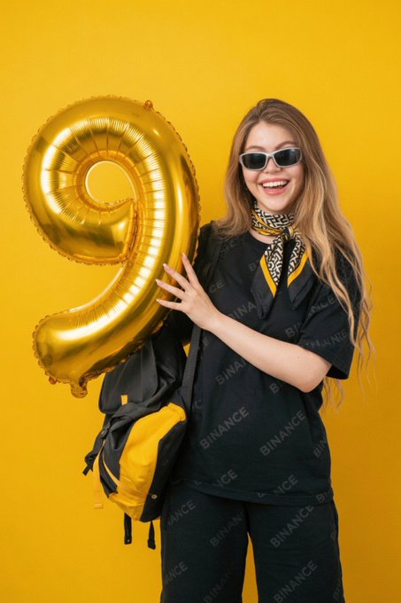 A smiling woman wearing sunglasses and 'BINANCE' branded black clothing poses with a yellow backpack and a large gold '9' balloon against a yellow background.