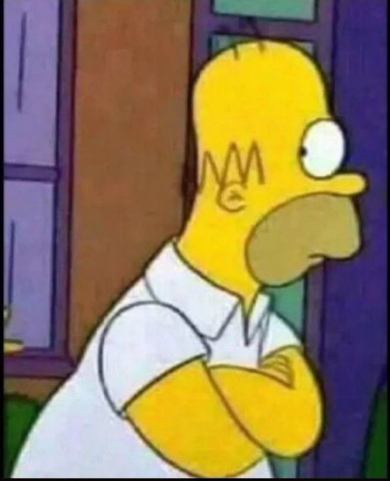A close-up frame of Homer Simpson from the animated series, looking wide-eyed with his signature zig-zag hairline visible, wearing a white polo shirt.