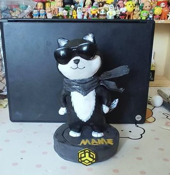 A custom figurine of a black and white cat wearing sunglasses and a scarf, mounted on a black base labeled 'MAME' with a hexagonal logo.