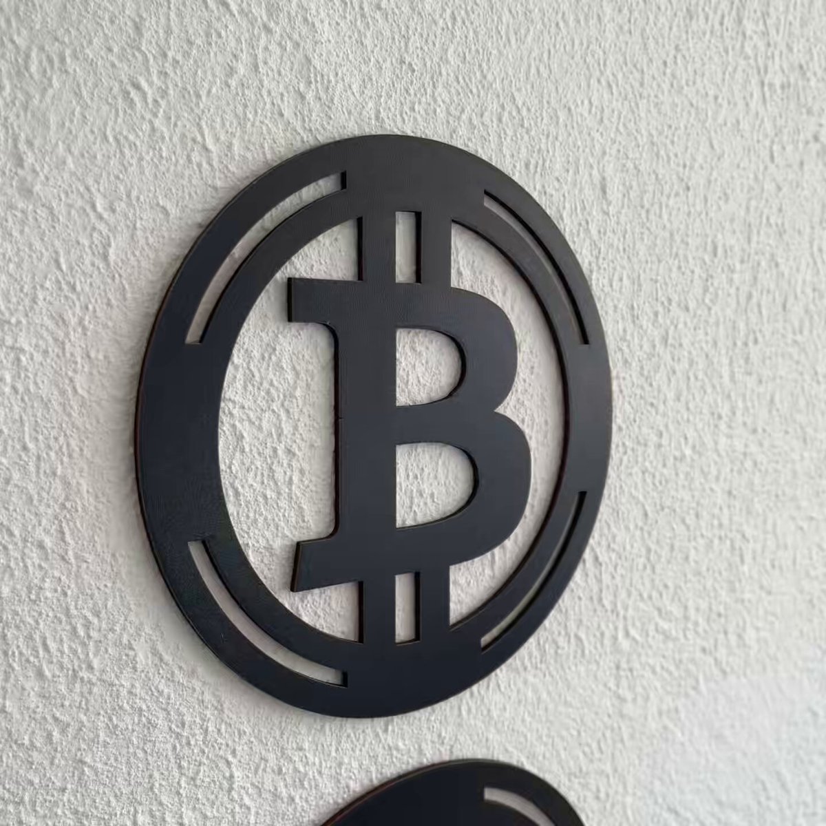 The image features a black circle with the letter "B" inside, which appears to be a logo or decoration. The background consists of a white wall, suggesting that this design could be used for various purposes such as branding, advertising, or even as an artistic statement. There are two other circles in the image, one located above and another below the main circle. These additional circles might serve as part of a larger design or simply be decorative elements within the scene. The post includes text that reads "Photoshoot day for @Plasma Card. Let's place it on top of @Revolut card and next to @KASTxyz". This suggests that the image could be used in a promotional context, possibly for a company or event related to cryptocurrency or digital currency.