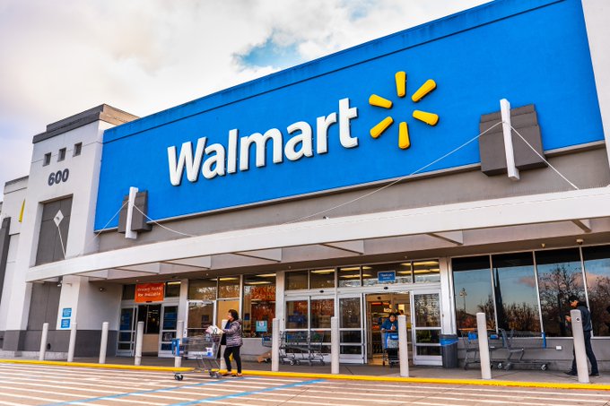 A Walmart storefront displays its logo and address "600" above the entrance, where shoppers and shopping carts are visible. The image accompanies a post highlighting Walmart's Q2 earnings beat, with adjusted EPS of $0.81 and revenue of $187.9B exceeding estimates.