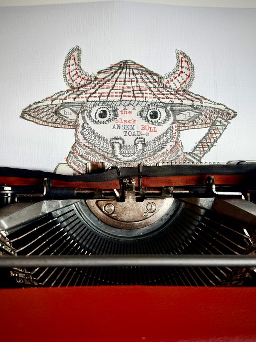 An illustration of a horned, monstrous head being typed on a piece of paper by an old-fashioned typewriter; the text on the paper reads 'the black ANSEM BULL TOAD-s'.