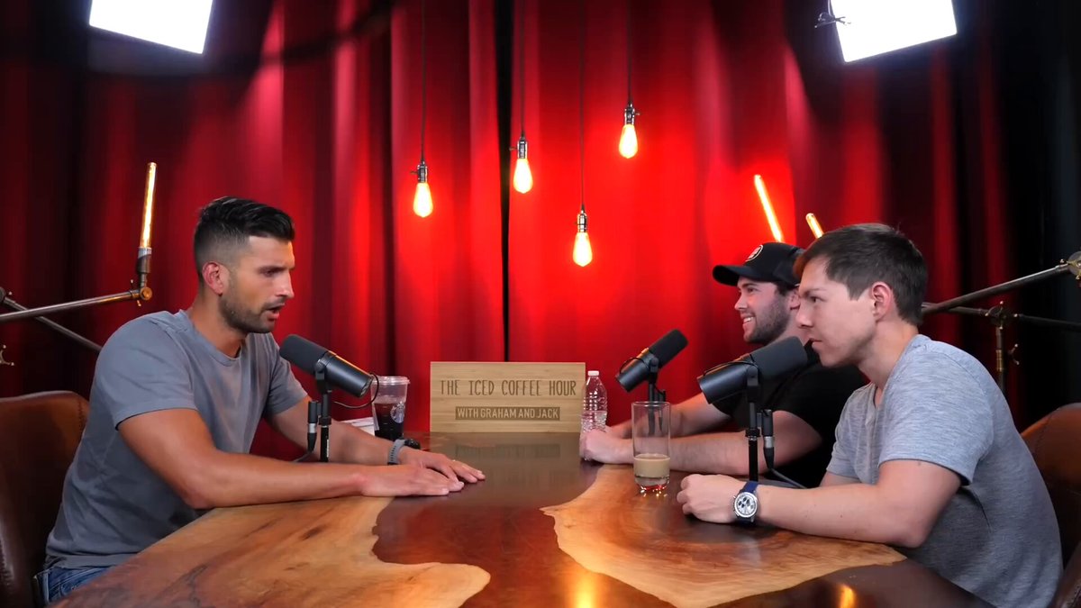 The image shows three men sitting around a table, engaged in conversation. The man at the center of the scene has a microphone in front of him, suggesting that they are participating in a podcast or radio show. One of the men appears to be talking about NFTs and crypto, which is relevant to Sahil Bloom's statement. 

There are two other people sitting on either side of the table, with one person on each side. The table has various items placed on it, including wine glasses and a cup. A clock can also be seen in the background, indicating that they might be discussing something related to time or events happening at different times.