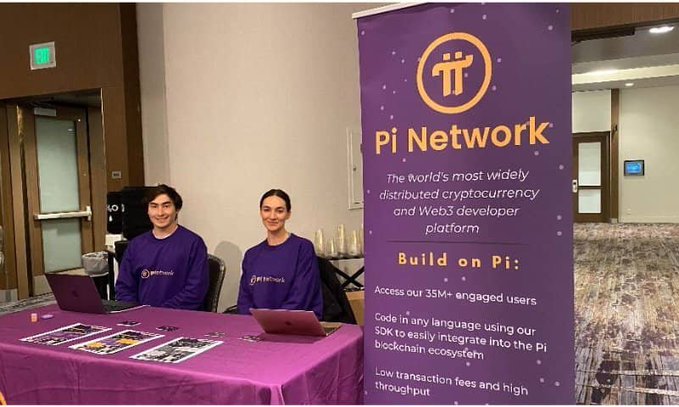 Two Pi Network representatives sit at a purple promotional booth displaying a banner touting "Pi Network – The world's most widely distributed cryptocurrency and Web3 developer platform," highlighting claims of 35M+ engaged users and a blockchain ecosystem. The image grounds the post's speculative scenario about a fully opened Pi ecosystem and an extraordinary $2 million per Pi valuation by showing the project's grassroots outreach presence, suggesting that the seemingly "impossible" price target could stem from the massive user base being actively recruited at events like this.