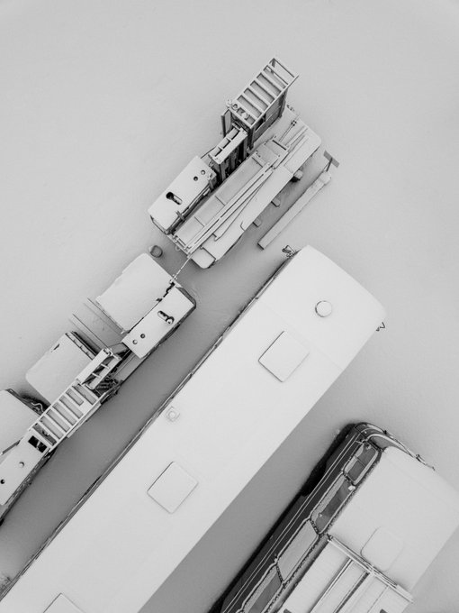A black and white aerial photograph of large industrial vehicles, appearing to be train cars or heavy machinery, covered in snow.