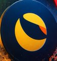 A close-up of a circular black and orange crescent logo set against a background of floating ash and embers.