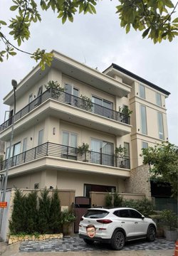 A modern multi-story residential building with balconies and a white SUV parked in front.