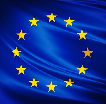 The flag of the European Union is depicted with its iconic circle of twelve gold stars on a blue background, representing the EU's enforcement of strict financial regulations including the €10,000 cash payment ban and mandatory ID requirements for Bitcoin transactions starting in 2027. The flag serves as a visual symbol of the EU's crackdown on financial privacy, which critics argue undermines individual freedom.
