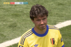 A small pixelated/sprite-style image of a soccer player with dark hair wearing a yellow jersey with black stripes, appearing to be from a retro football video game, with a BBC Sport scoreboard visible at the top showing 'SCO 2 1 BEL HT'.