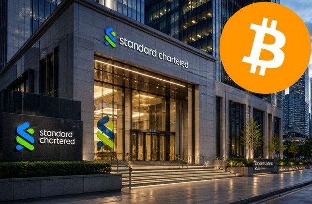 The image features a large white building with Standard Chartered's logo displayed prominently above its entrance. Below this, there are two logos - one of a Bitcoin symbol and another of an orange Bitcoin icon. The text "Standard Chartered" appears on both logos, indicating that it is associated with the cryptocurrency. The Bitcoin icons suggest an association or investment interest in Bitcoin within Standard Chartered's operations. The large size of these icons indicates they are designed to grab attention and signify importance.