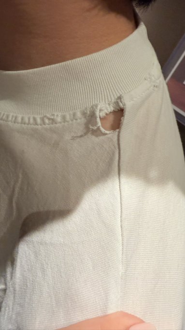 A close-up photo showing a damaged cream-colored garment with a torn pocket near the waistband, held up to the camera.
