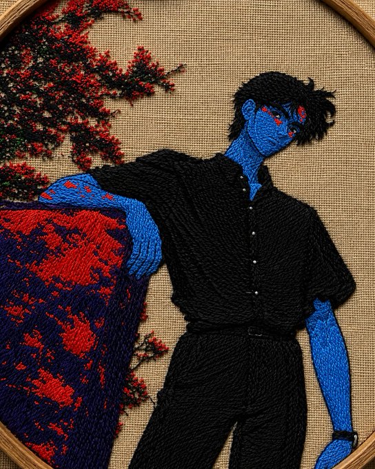 An embroidered artwork depicting a blue-skinned character with dark hair and red eyes, wearing a black shirt and pants, set against a backdrop of red flowering branches.
