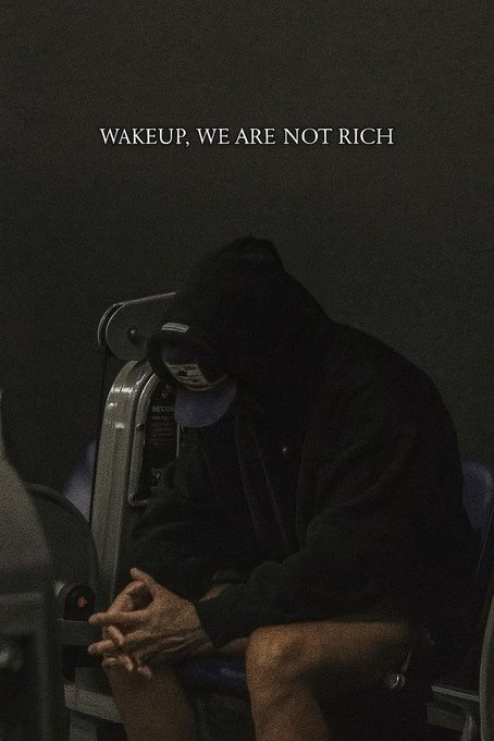 A moody, dark photograph of a person in a black hoodie and cap seated with hands clasped, accompanied by the text 'WAKEUP. WE ARE NOT RICH.'