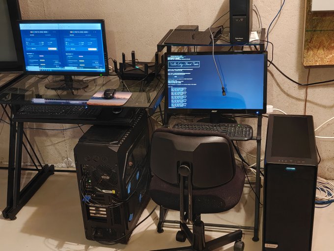 A home computer setup with dual monitors displaying code and system information, alongside a desktop PC tower and a black office chair, supporting the poster's achievement of running a stable Theta Network EdgeCloud inference node for over 72 hours.