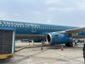 A Vietnam Airlines aircraft is parked at an airport gate with the airline's name visible on the fuselage.