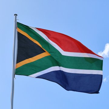 The South African flag waves against a blue sky, symbolizing the country's regulatory authority over cross-border crypto transactions as proposed by its financial oversight bodies.