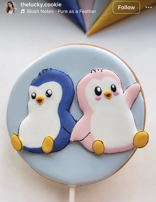 The image features two penguin-shaped cookies sitting side by side on a plate. They are decorated with blue icing and yellow accents, giving them a playful appearance. The text "PM" appears at the bottom of the image, which could be a part of a social media post or a message from someone who made these cookies. The caption asks if people would eat these cookies or if they love penguins too much not to.