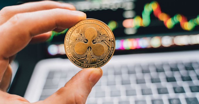In the image, a person's hand is holding up a golden coin featuring the symbol of Ripples. The coin is set against the backdrop of an open laptop computer displaying financial data related to RippleCoins. RippleCoins has been moving sideways in recent weeks between $1.05 and $1.15, with both ETF inflows andRLUSD growth not enough to shake it loose. This suggests that Ripple's network keeps humming along as its price continues to rise without any apparent reaction from the market.