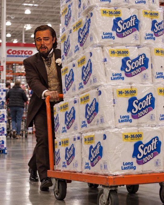 A man dressed in a 19th-century tuxedo pushes a hand truck loaded with a large stack of Scott 1000 toilet paper packages inside a Costco warehouse.