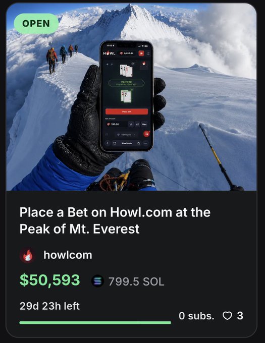 The image depicts a person holding up their phone displaying an image of someone playing a game at the peak of Mount Everest. The advertisement for this gaming platform invites people who are climbing Everest to participate by recording themselves playing the game, which could lead to a substantial cash reward if they succeed in completing the challenge and winning the top prize of $50,000.