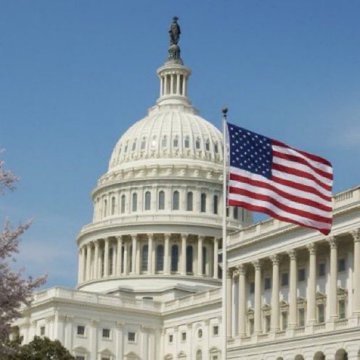 The image shows the United States Capitol Building with its iconic white dome and an American flag waving in the foreground, symbolizing the bipartisan legislative discussions mentioned in the post. The accompanying text references Trump White House officials reviewing Bitcoin and cryptocurrency ethics terms, supported by Senators Tillis (R) and Gallego (D), suggesting imminent legislative action on digital asset policy.
