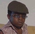 Low-resolution photo of a person wearing a green beanie, sunglasses, and a patterned shirt.