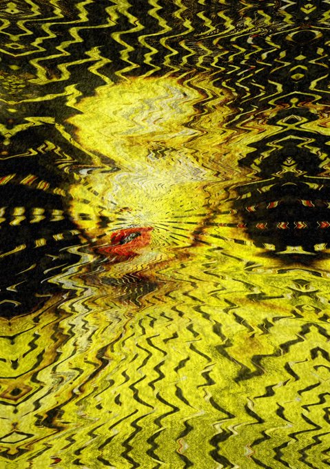 An abstract, heavily distorted image with wavy, rippling patterns in vibrant yellow and black, with a small patch of red near the center.