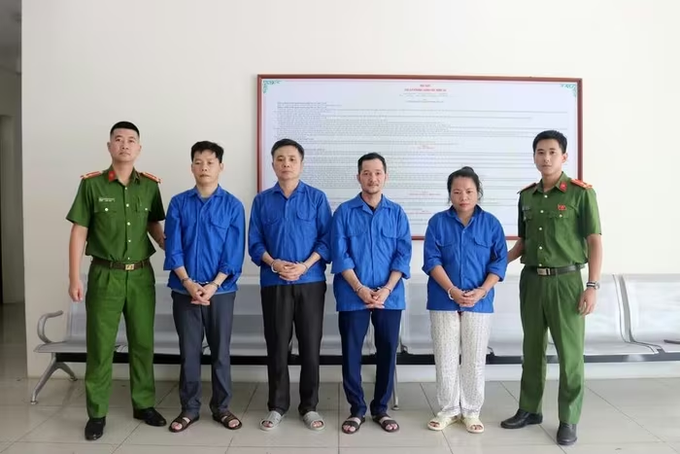Six individuals—two uniformed officers and four people in blue shirts—stand before a large whiteboard covered with Vietnamese text, likely presenting details of the CVX crypto investment case.