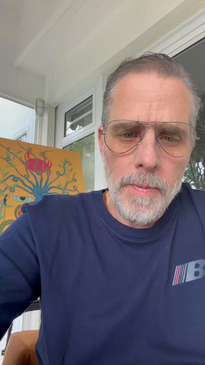 The image features a man wearing glasses, a blue shirt with a red stripe, and sitting on a porch or deck outside of a house. The photo has been edited to include text that reads "You degens are so desperate for a meta in the trenches that you’ll actually listen to this idiot." This alteration suggests that the image may have been manipulated to convey a message about the man's situation, possibly related to his job or personal life.