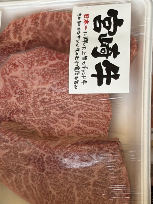 A package of high-quality Japanese A5 wagyu beef, identifiable by its heavy marbling and a label with prominent Japanese calligraphy.