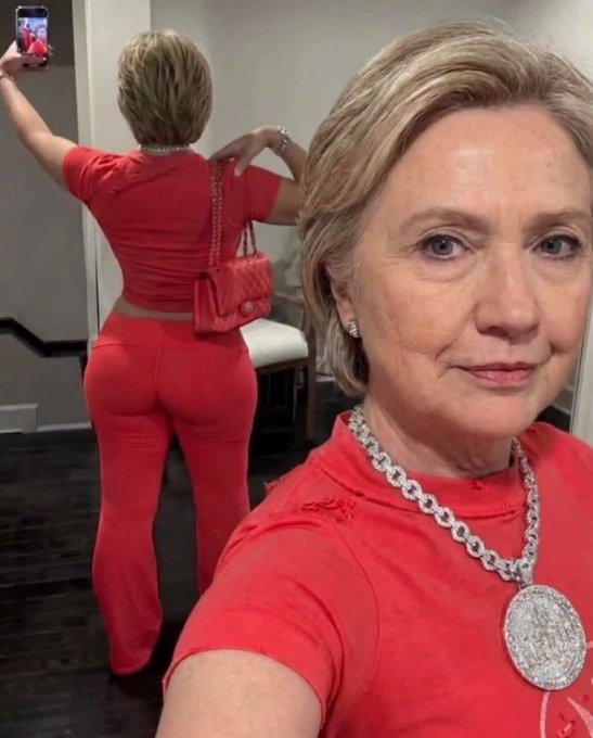 The image features a woman wearing red clothing, including a short sleeve shirt and pants, as well as a necklace with a large pendant. She is taking a selfie using her cell phone, capturing herself in the mirror. The caption of the image reads "hyperliquid. $HYPE". This suggests that the photo has been edited or manipulated to create an unrealistic or exaggerated appearance for the purpose of promoting a product or service.