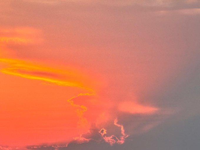 A sunset sky displays vibrant orange and pink clouds with sun rays illuminating the colorful atmosphere.