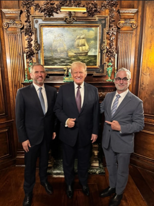 The image shows three men in suits posing together in an ornately decorated room with wood paneling and a maritime painting in the background, likely taken at a high-level political or diplomatic venue. Based on the post's context, this appears to be a photo linking Ripple's Washington DC presence to proximity with government leadership, including the President, to support claims about Ripple's strategic political positioning.

No visible text, names, or identifying details appear in the image itself.