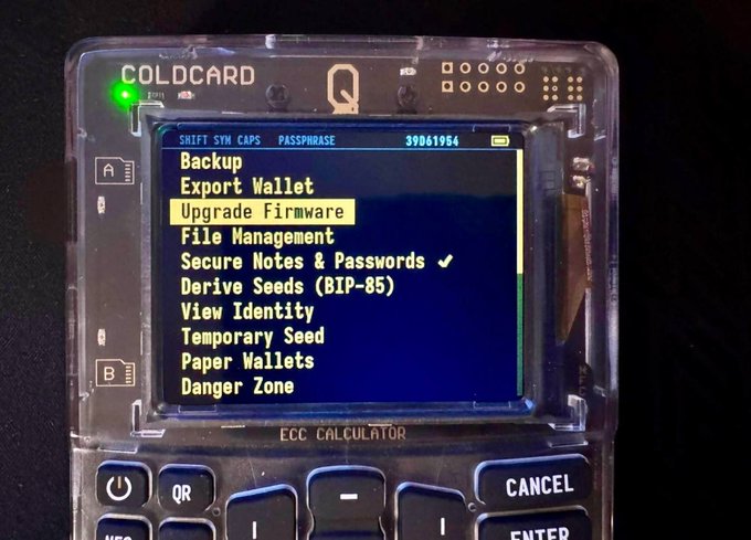 A COLDCARD Q hardware cryptocurrency wallet displaying its menu screen with options including 'Upgrade Firmware' highlighted, along with 'Backup', 'Export Wallet', and 'Secure Notes & Passwords'.
