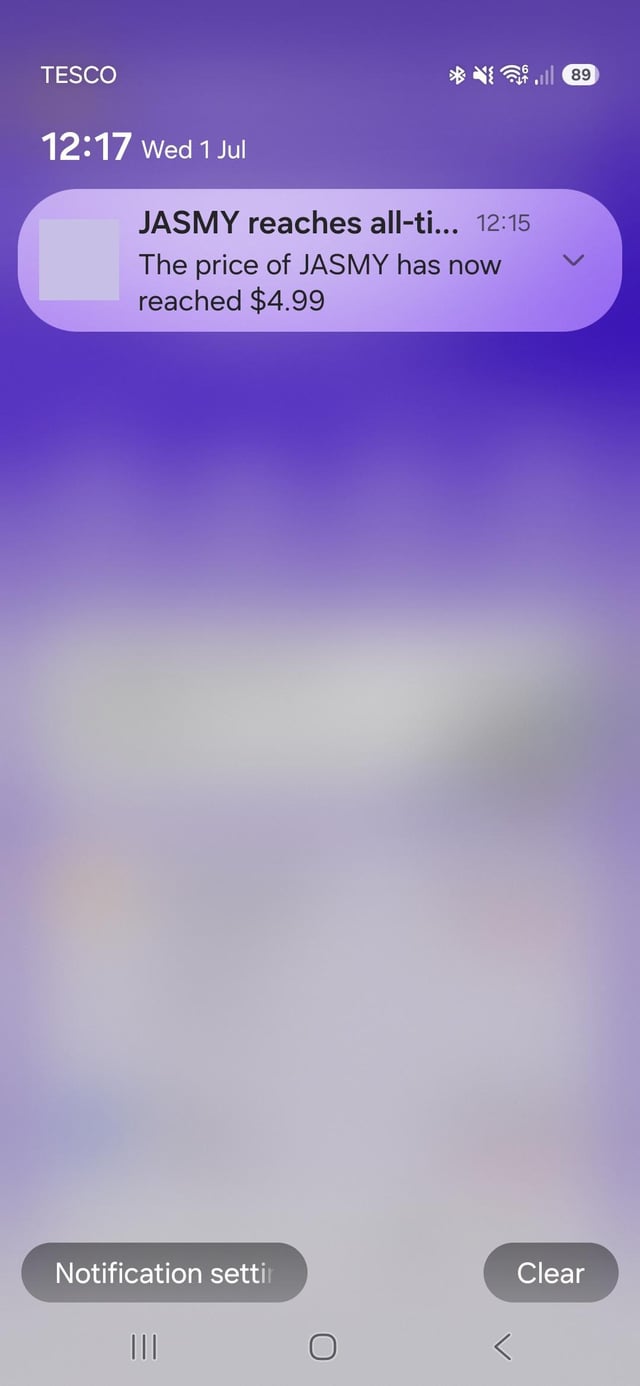 A smartphone lock screen notification from TESCO at 12:17 on Wed 1 Jul reading 'JASMY reaches all-ti... The price of JASMY has now reached $4.99'.