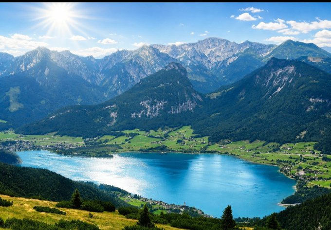 A scenic mountain landscape with a bright blue lake and sun shining, symbolizing the "TOP" where the post suggests meeting after the "BOTTOM" was too crowded, referring to the #BTC and #XRP tickers.