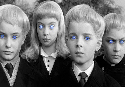 A black-and-white photo of four children with blonde hair and dark school uniforms, their eyes edited to glow bright blue.